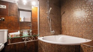 Un baño moderno con un lavabo con revestimiento de vidrio, una bañera independiente y una ducha con cerramiento de vidrio.