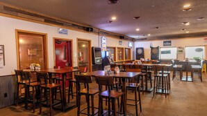 A restaurant with multiple tables and chairs, a dartboard, and a sign for Bud Light. - Black Hills Station  (Piedmont)