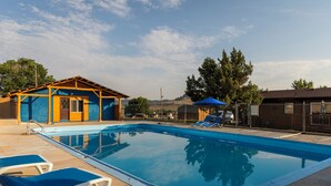 A swimming pool with lounge chairs and a small building with a blue roof. - Black Hills Station  (Piedmont)