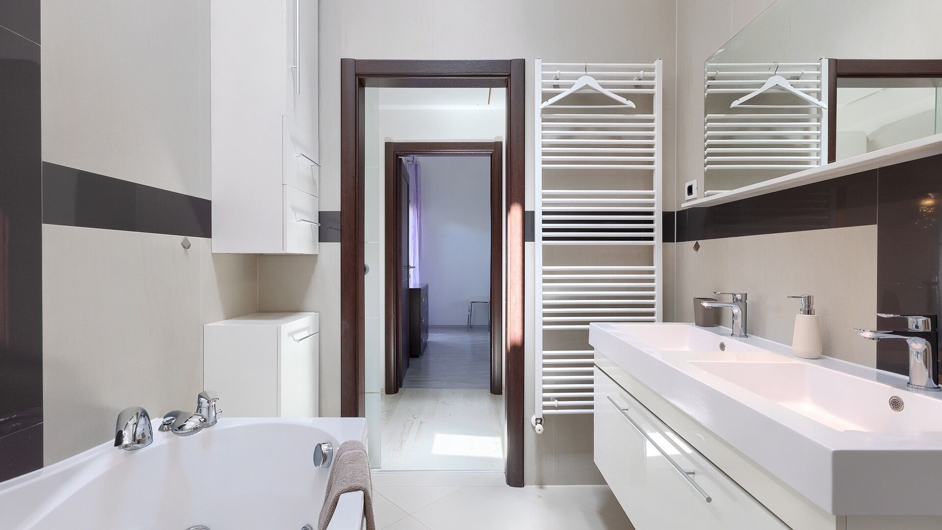 A modern bathroom with a bathtub, two sinks, and a walk-in shower.