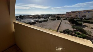 A balcony with a view of a residential area, including houses and a road. - Charming T2 in residence with swimming pool (Fleury)