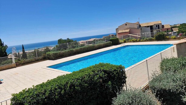 A swimming pool with a view of the sea and a Ferris wheel in the background. - Charming T2 in residence with swimming pool (Fleury)
