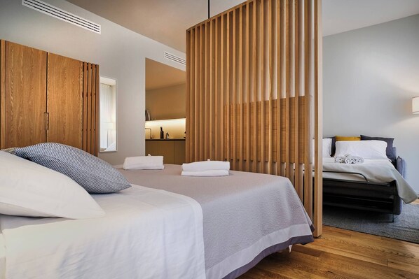 A modern hotel room with two beds, wooden paneling, and a visible bathroom.