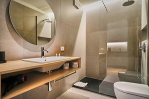 A modern bathroom with a round mirror, a sink, a shower, and a toilet.