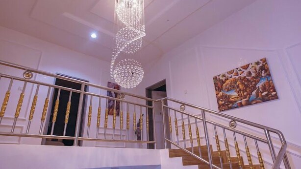 A staircase with a chandelier and a painting on the wall. - Hiltons Bellaire (Abuja)