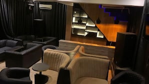 A modern living room with dark curtains, a sofa, a coffee table, and a staircase with blue lighting. - Hiltons Bellaire (Abuja)
