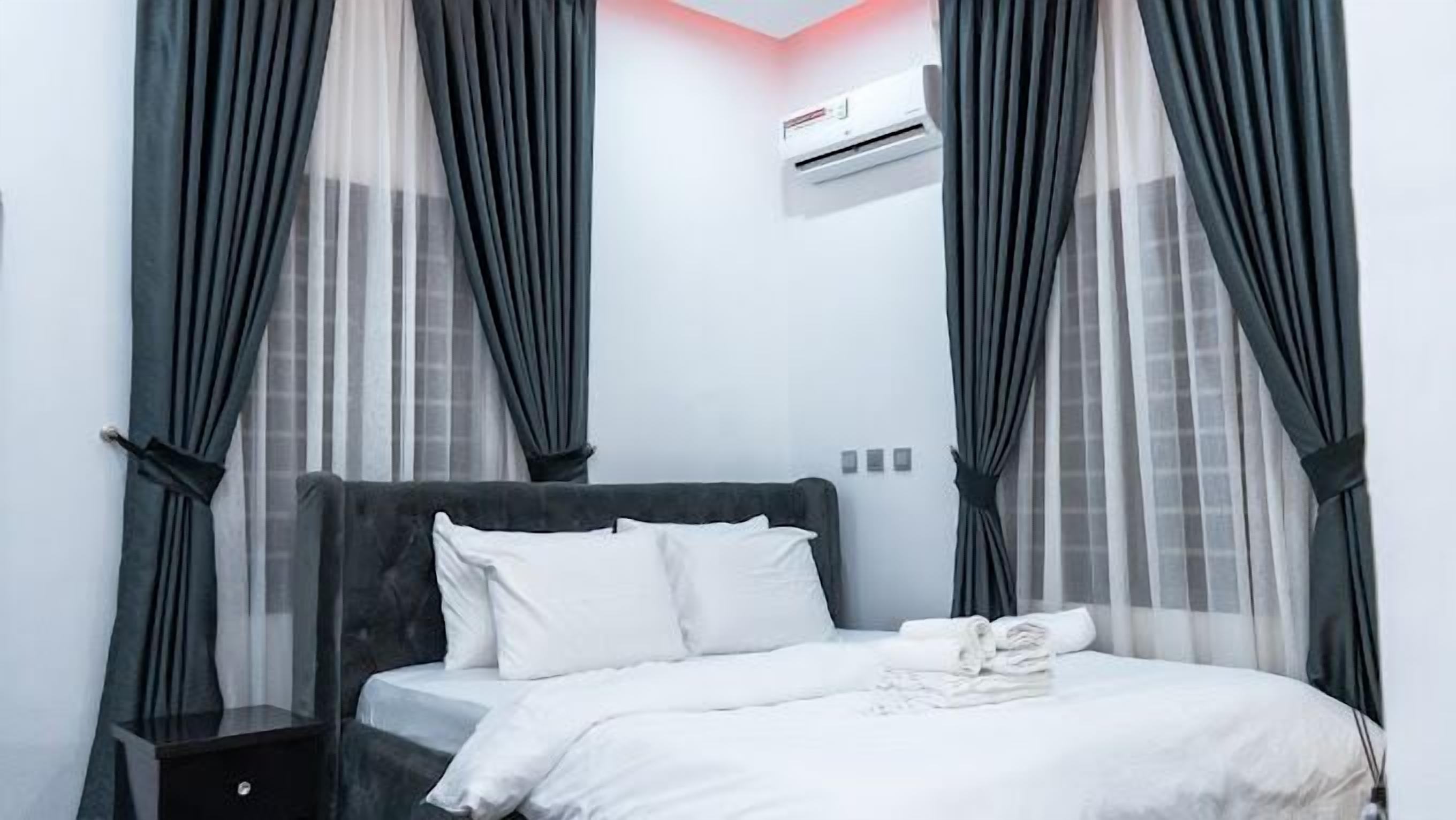 A neatly made bed with white linens, a dark headboard, and a small bedside table.