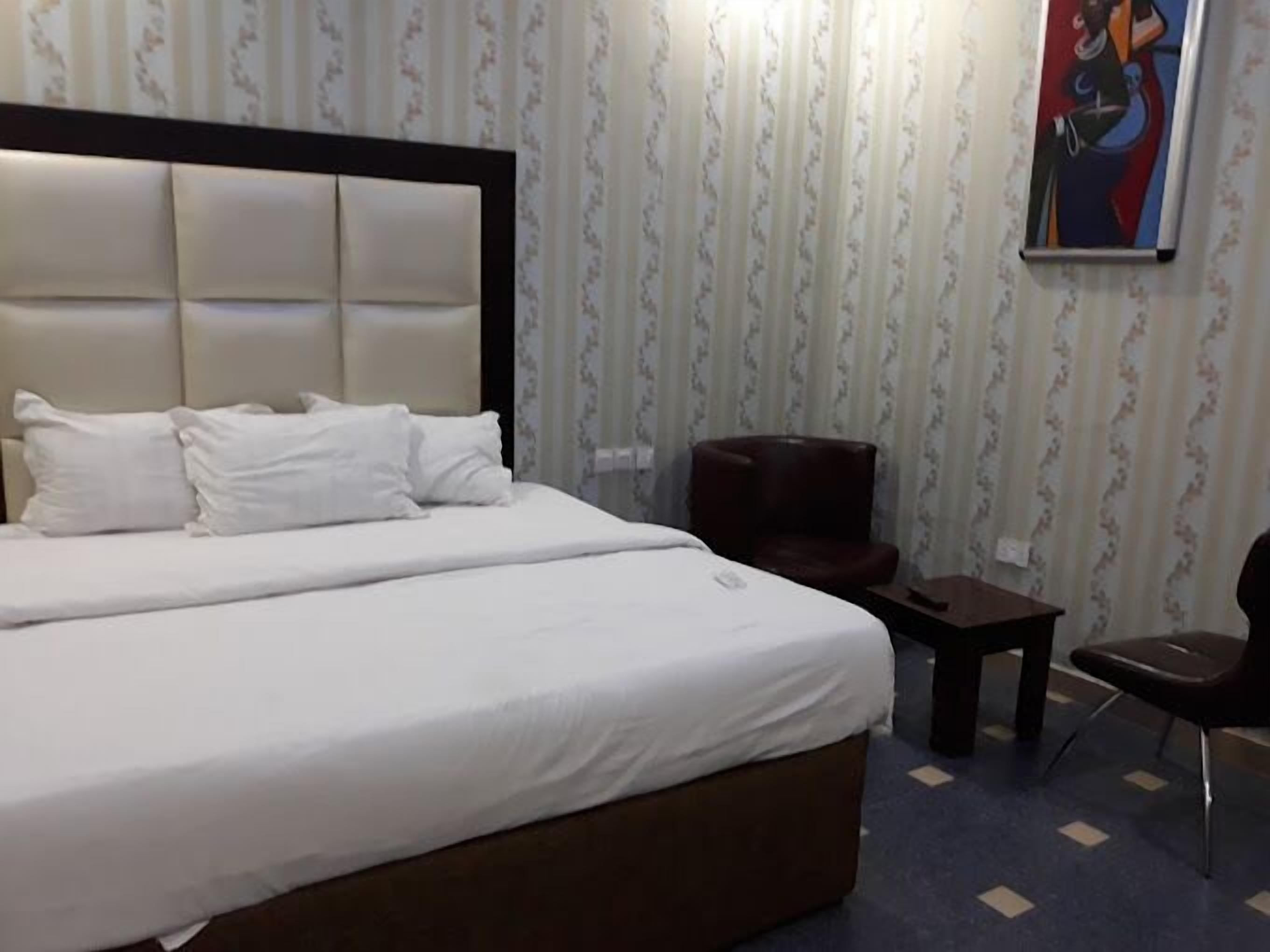 Une chambre d’hôtel avec un grand lit, une petite table, une chaise et un tableau au mur.