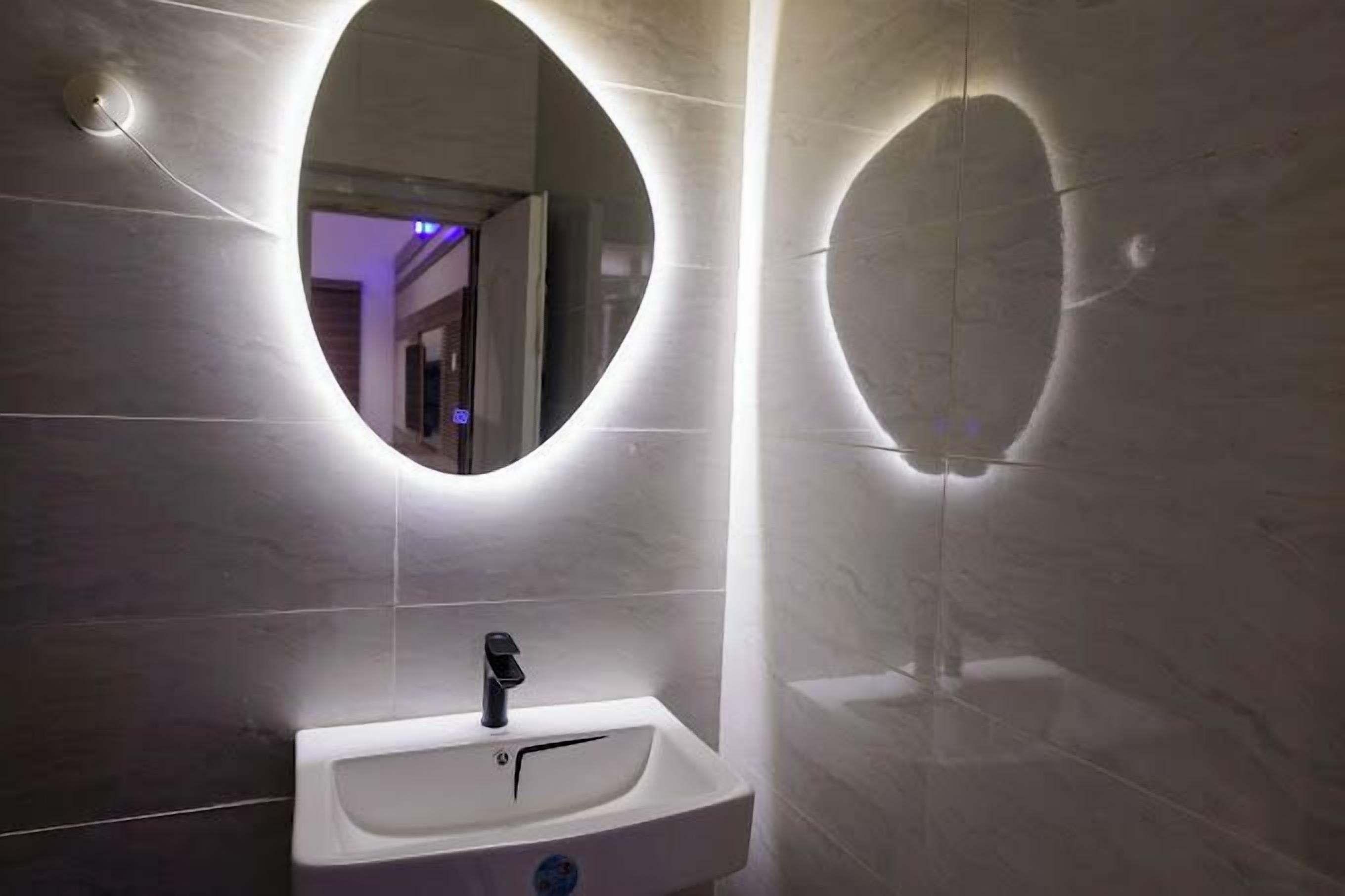 A bathroom with a white sink, a mirror, and a light fixture above the mirror.