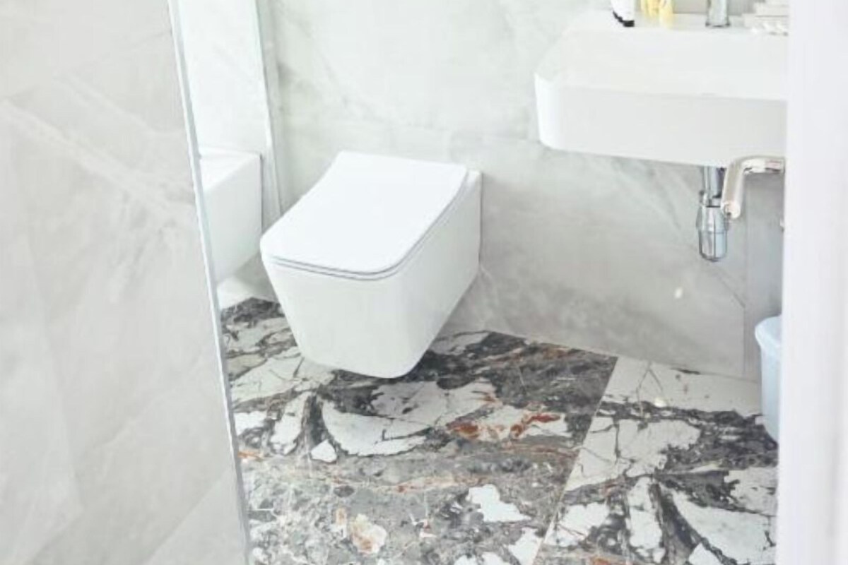 A bathroom with a toilet, sink, and marble flooring.