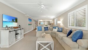 A spacious living room with a large flat-screen TV, a ceiling fan, and a cozy sectional sofa. - Sanibel Beachfront Luxury Condo Full Gulf View! 3BR, 2 BA! Covered Prkg! Sports! (Sanibel)