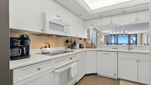 A modern kitchen with white cabinetry, a built-in microwave, a kettle, and a coffee maker. - Sanibel Beachfront Luxury Condo Full Gulf View! 3BR, 2 BA! Covered Prkg! Sports! (Sanibel)