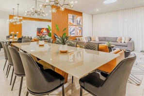 Un comedor moderno con una gran mesa rectangular, varias sillas y una planta central.
