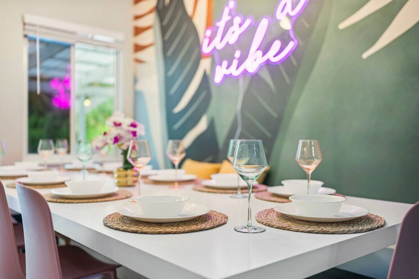 A dining table set with white plates, clear glasses, and woven placemats.
