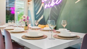 A dining table set with white plates, clear glasses, and woven placemats. - PalmParadise: 5BR Family&Pet Fun, HeatedPool&Games (West Palm Beach)