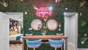 A room with a green wall, two round mirrors, a neon sign, and a bed with a colorful headboard. - PalmParadise: 5BR Family&Pet Fun, HeatedPool&Games (West Palm Beach)