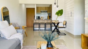 Ein modernes Wohnzimmer mit einem grauen Sofa, einem Couchtisch mit Dekoration und Blick in den Küchenbereich.