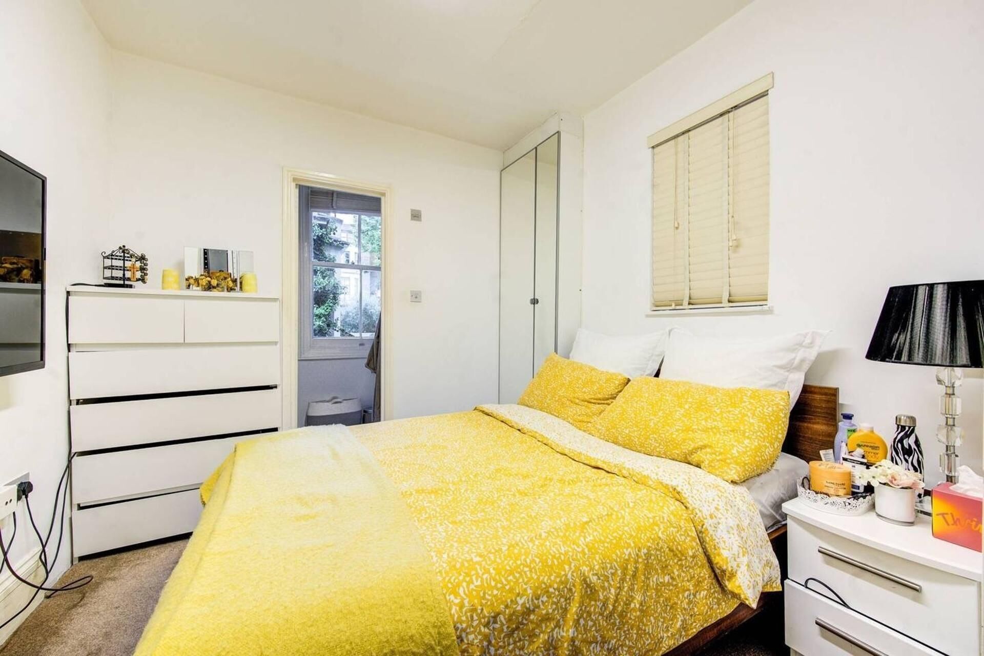 A bedroom with a bed, bedside table, and a wardrobe.
