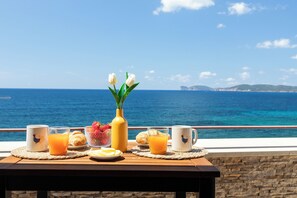 A breakfast table with croissants, orange juice, and a vase of flowers, overlooking a coastal view. - Romantic Seaside Loft Sardinia – Panoramic Sea View for Couples (Alghero)