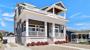 Une maison à deux étages dotée d’un balcon, d’un porche couvert et d’une petite dépendance attenante, elle aussi pourvue d’un porche.