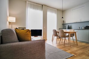 Uma sala moderna com sofá, televisão e área de jantar com cadeiras e mesa.