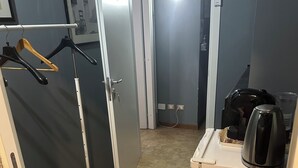 A small, compact hotel room with a kitchenette, a door leading to another room, and a coat rack with hangers. - SINGLE APARTMENT 700 METERS FROM THE CENTER OF MILAN (Milano)