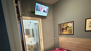 A bedroom with a bed, a TV mounted on the wall, a painting, and a door leading to a bathroom. - SINGLE APARTMENT 700 METERS FROM THE CENTER OF MILAN (Milano)
