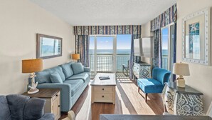 A room with a sofa, a coffee table, and a TV. There is a balcony with a view of the sea. - Bay Watch Resort 1540-Oceanfront 2BR/2BA- Pools (North Myrtle Beach)