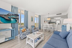 A modern living room with a pool view, a dining area, and a kitchen.