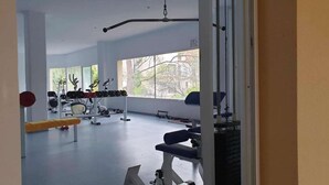 Une salle de sport équipée de divers appareils d’exercice, dotée de grandes fenêtres et offrant un espace propre et spacieux.