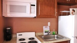 A compact kitchen with a white microwave, stove, and sink. - Charming studio in delightful Orlando with WiFi and AC (Orlando)