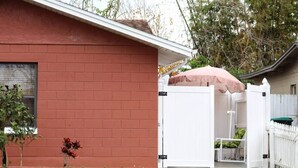 A red brick house with a white fence and a covered patio area. - Charming studio in delightful Orlando with WiFi and AC (Orlando)
