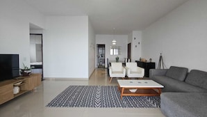 A modern living room with a grey sofa, two white armchairs, a coffee table, and a TV on a wooden stand. - Charming apartment with sea view in Copacabana (Ipanema Rio de Janeiro)
