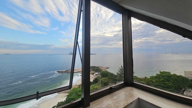 A room with a large window overlooking a beach and ocean. - Charming apartment with sea view in Copacabana (Ipanema Rio de Janeiro)
