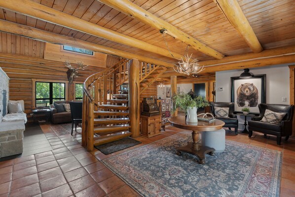 Interior de madera con una escalera de caracol, una chimenea y un cuadro de un oso.