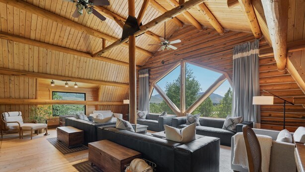 A spacious wooden cabin interior with a large sofa, a wooden coffee table, and a ceiling fan. - Snowberry Inn: Large Kitchen & Gathering Room 9BR 11BA Ensuite bath in all rooms (Eden)
