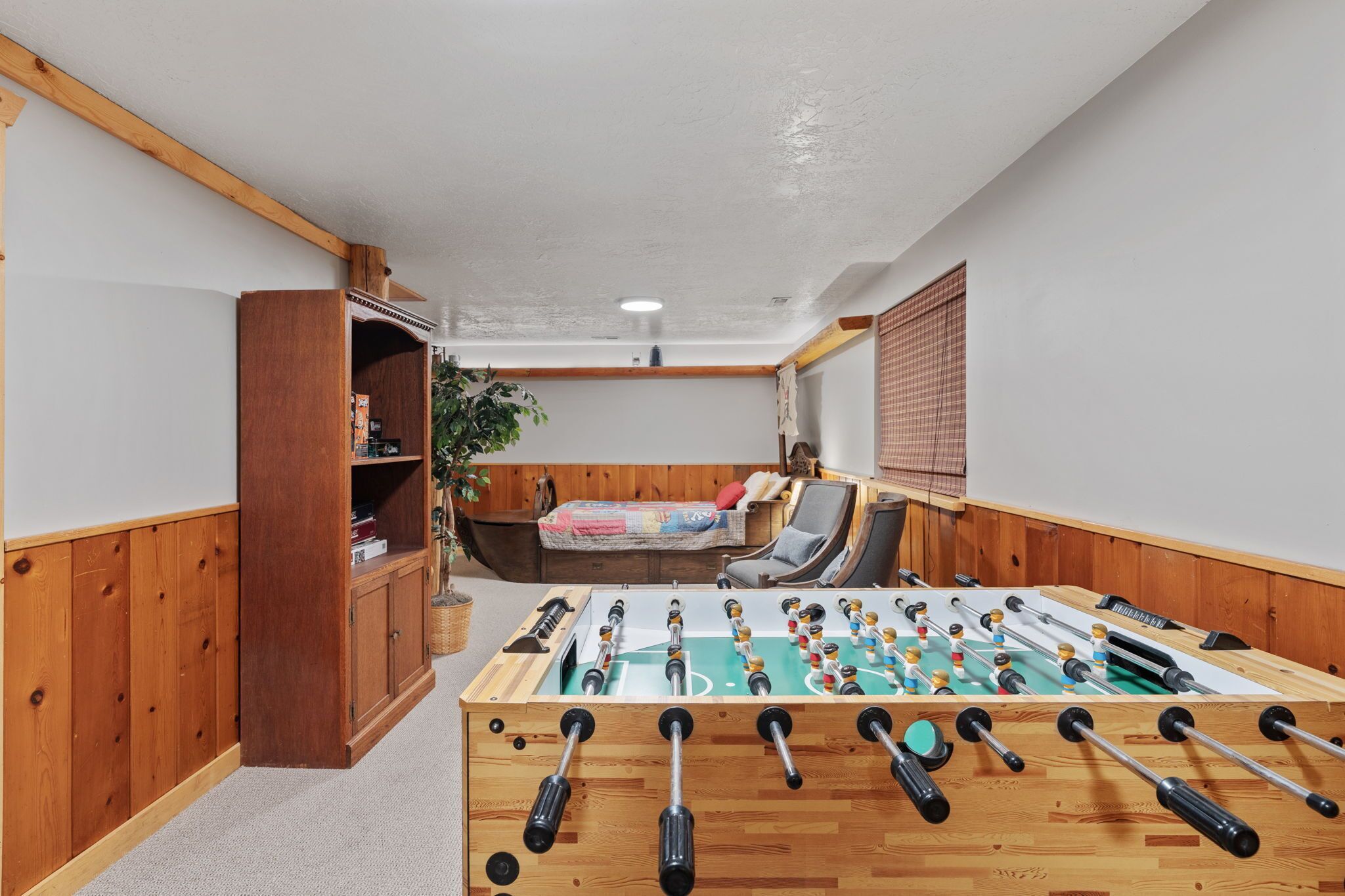 Une pièce chaleureuse avec un baby-foot, des meubles en bois et un coin salon confortable.
