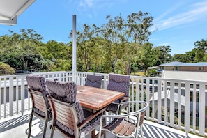 Een balkon met een houten tafel en stoelen, omringd door een witte hek.