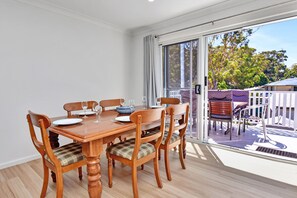 A dining area with a wooden table and chairs, a sliding glass door leading to an outdoor patio.