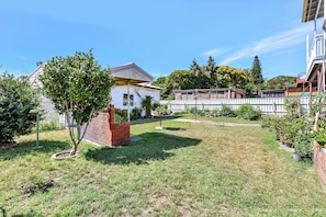 A residential property with a fenced yard, a small brick structure, and a tree.