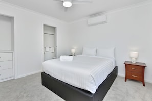 A bedroom with a bed, bedside tables, a wardrobe, and a ceiling fan.