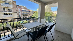 A balcony with a table and chairs, overlooking a residential area with multi-story buildings. - APARTMENT T3 AIR-CONDITIONED FOR RENT FOR 4 PEOPLE IN THE CITY CENTER (STE MAXIME)
