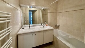 A modern bathroom with two sinks, a large mirror, and a bathtub. - APARTMENT T3 AIR-CONDITIONED FOR RENT FOR 4 PEOPLE IN THE CITY CENTER (STE MAXIME)