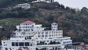A multi-story hotel with a central courtyard, surrounded by lush greenery and hills. - Hotel zurapalace (Batumi)