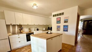 A modern kitchen with white cabinets, a central island, and a tiled floor.