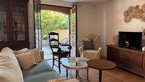 A living room with a sofa, a chair, a small table, a television, and a cabinet. - Villa Caline | Wi-Fi, Clim, 150 m from the beach (Lucciana)