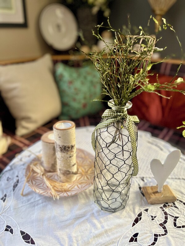 A table with a glass vase containing dried flowers, a candle, and a decorative heart. - Apart Hotel Goldener Hahn Baiersbronn, Ferienwohnungen | Frühstück, Sauna & Indoorpool (Baiersbronn)