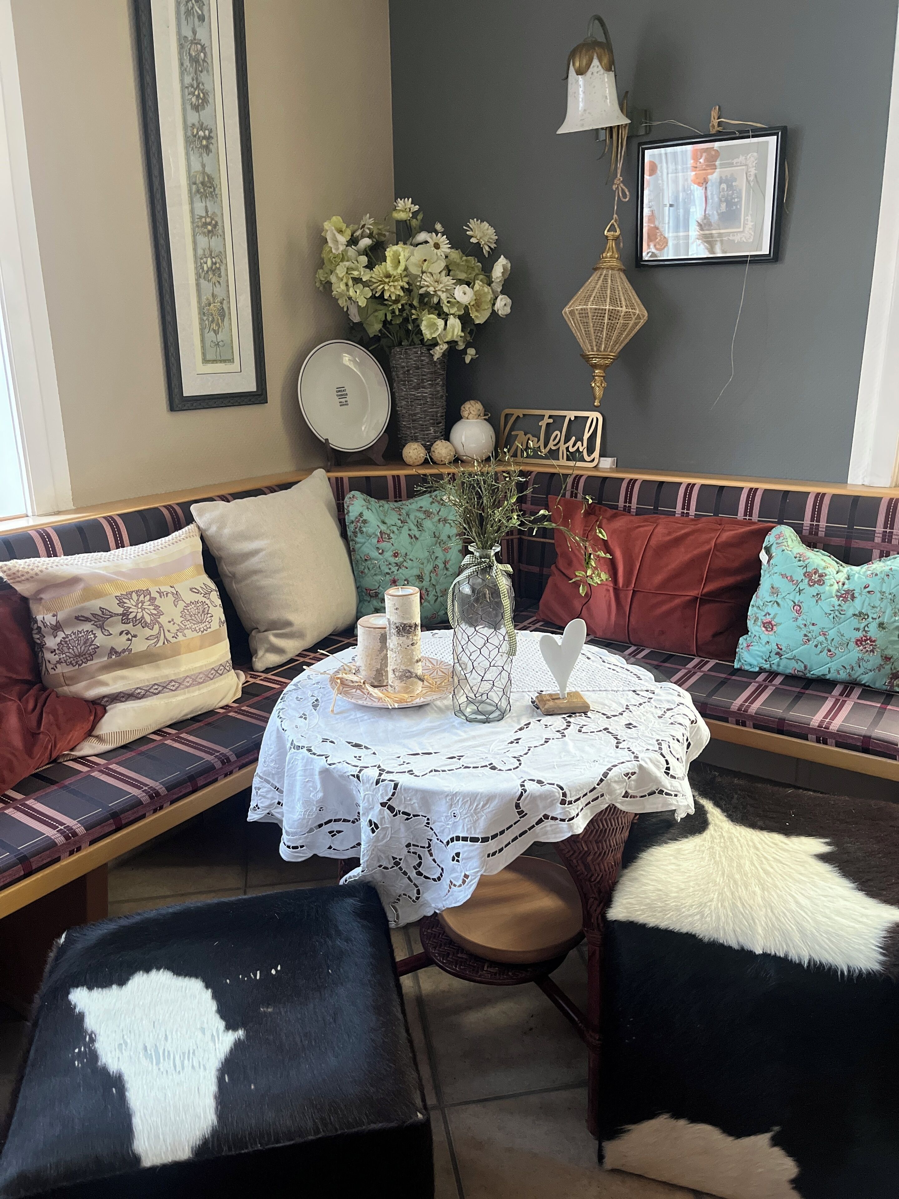 A cozy seating area with a bench, ottoman, and a table with a lace tablecloth.
