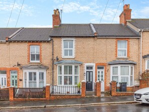 A row of terraced houses with brick facades, white window frames, and a gated entrance.