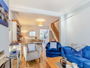 A modern living room with a sofa, armchair, coffee table, and a dining area with a table and chairs. - 2 bedroom accommodation in Weymouth (Weymouth)